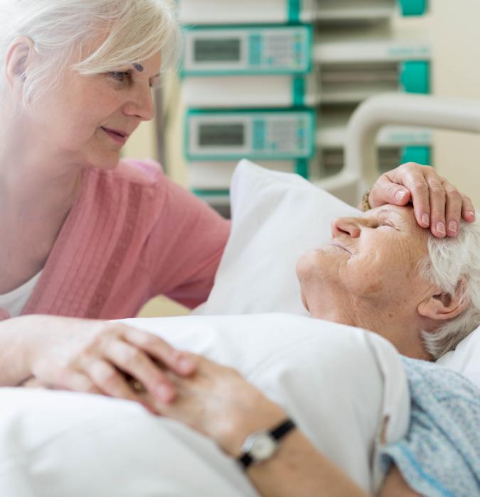 An older man receiving care in a hospital bed.